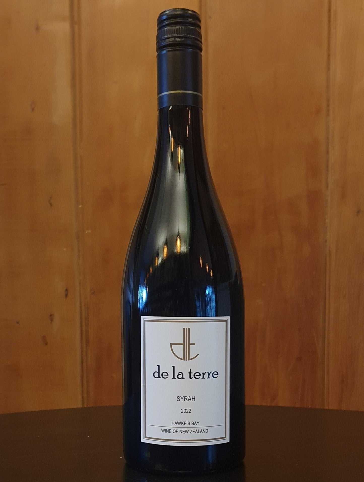 Wine bottle with 'de la terre' label on a wooden background