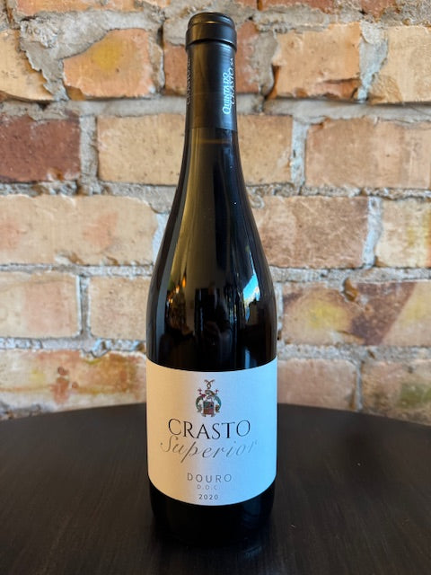 Wine bottle with a label on a brick wall background.  The label reads Crasto Superior in big letters.