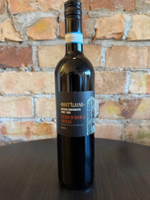 Wine bottle with a dark black and gold label on a brick surface