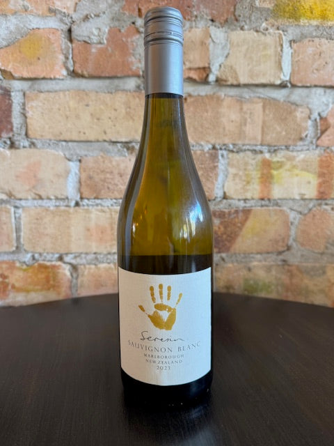 Wine bottle with a label on a brick surface. The label shows a big yellow hand print with small text "Seresin' underneath.