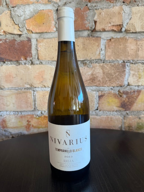 Wine bottle with a label on a brick surface.  The label is plain white with big gold text saying Nivarius.