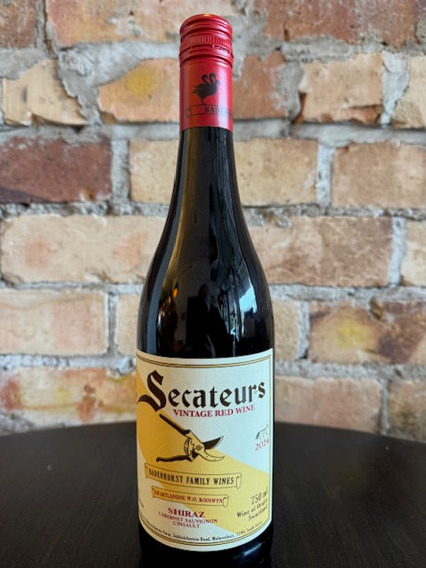 Bottle of Secateurs wine with a red cap against a brick wall background