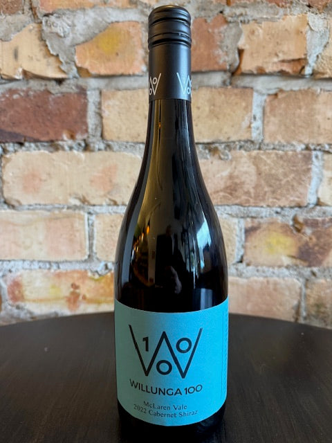 Wine bottle with a blue label featuring a big W logo against a brick wall background