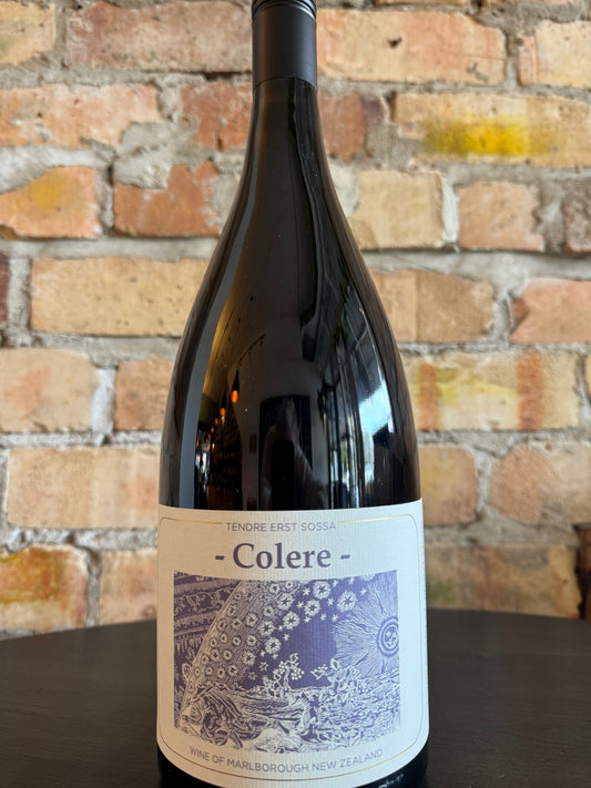 Wine bottle labeled 'Colere' against a brick wall background
